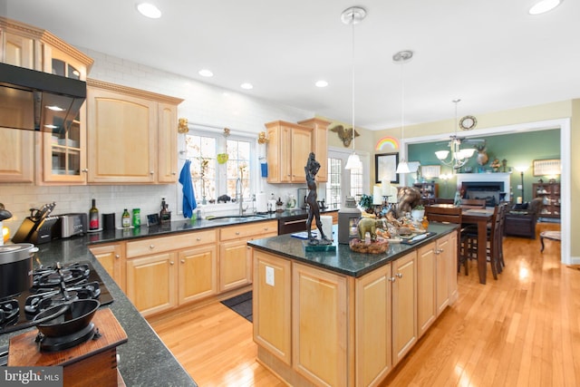 kitchen with sink, hanging light fixtures, light hardwood / wood-style floors, decorative backsplash, and light brown cabinetry