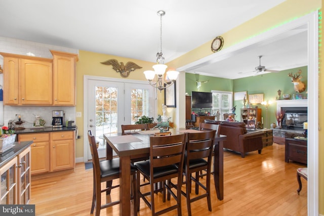 dining room with ceiling fan with notable chandelier and light hardwood / wood-style floors