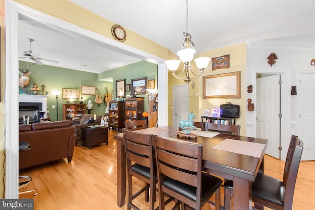 dining space featuring crown molding, light hardwood / wood-style floors, and ceiling fan with notable chandelier