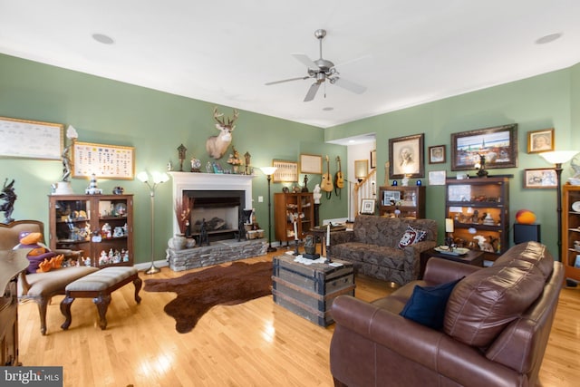 living room with ceiling fan, a fireplace, and light wood-type flooring