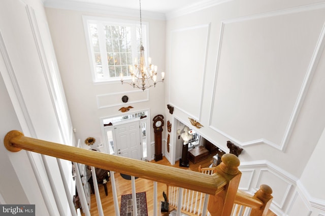 stairs featuring wood-type flooring, a chandelier, and ornamental molding