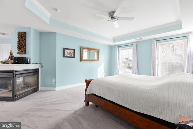 carpeted bedroom with a tray ceiling, ceiling fan, and ornamental molding