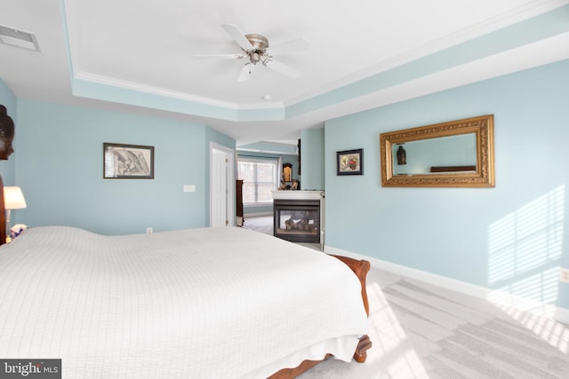 bedroom featuring a tray ceiling, ceiling fan, crown molding, and carpet