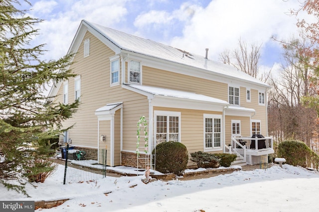 snow covered house featuring a wooden deck