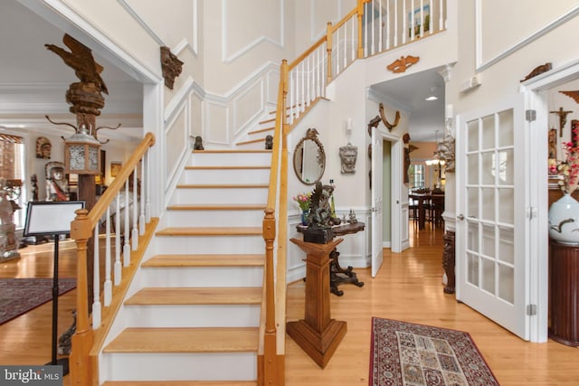 stairway with a towering ceiling, hardwood / wood-style flooring, and ornamental molding