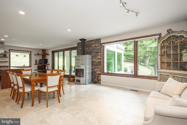 dining area featuring track lighting, a wood stove, and plenty of natural light