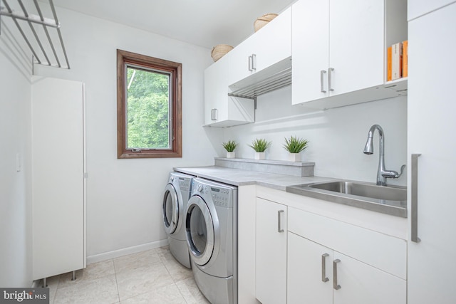 laundry area with cabinets, light tile patterned floors, washing machine and dryer, and sink