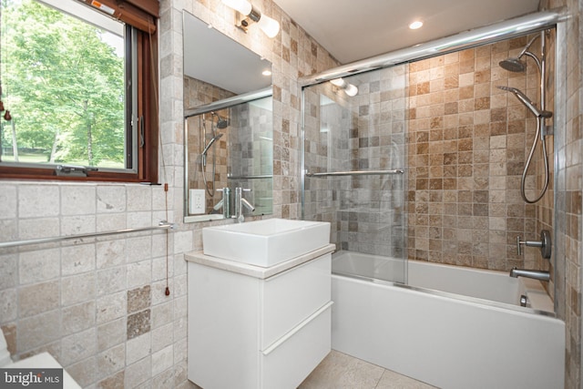 bathroom featuring tile patterned floors, combined bath / shower with glass door, sink, and tile walls