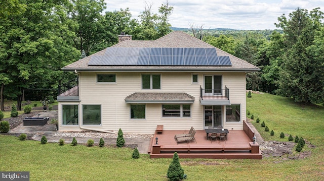 back of house with solar panels, a yard, a balcony, and a deck