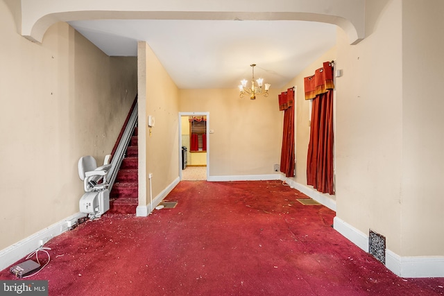 carpeted empty room featuring a notable chandelier