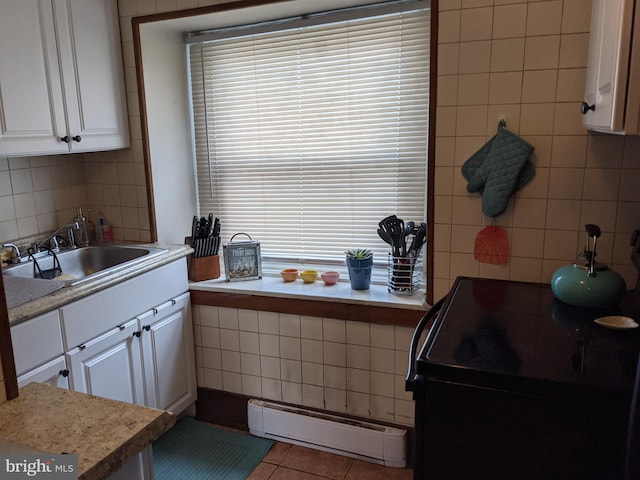 kitchen featuring backsplash, white cabinets, sink, tile patterned flooring, and baseboard heating