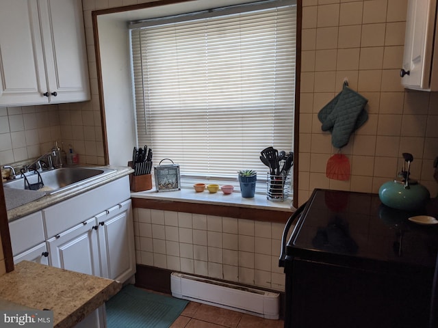 kitchen featuring white cabinets, tile patterned floors, baseboard heating, and sink