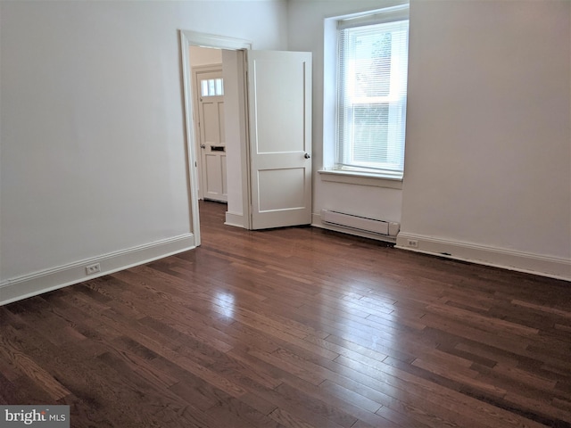 spare room featuring dark wood-type flooring and a baseboard heating unit