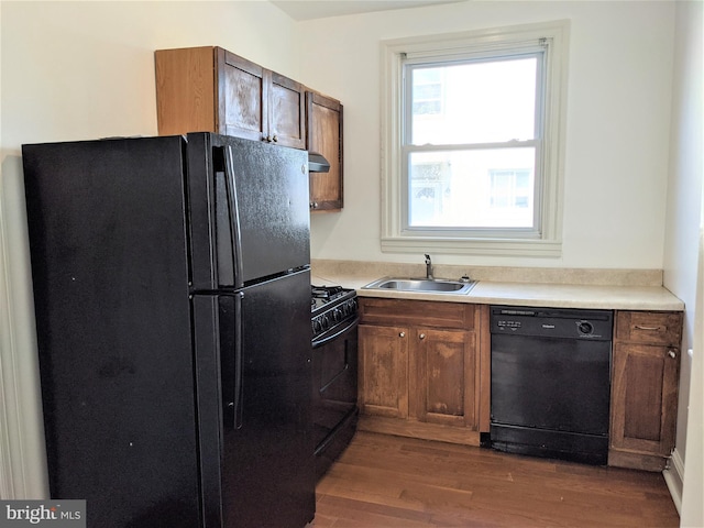 kitchen featuring exhaust hood, sink, black appliances, and dark hardwood / wood-style floors