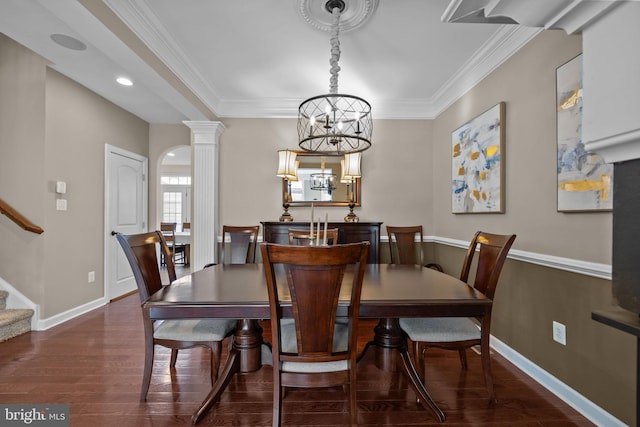 dining room featuring an inviting chandelier, crown molding, dark wood-type flooring, and ornate columns