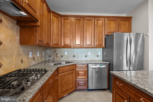 kitchen with sink, backsplash, light stone countertops, and appliances with stainless steel finishes