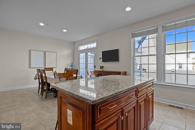 kitchen with french doors, light stone counters, light tile patterned flooring, and a kitchen island