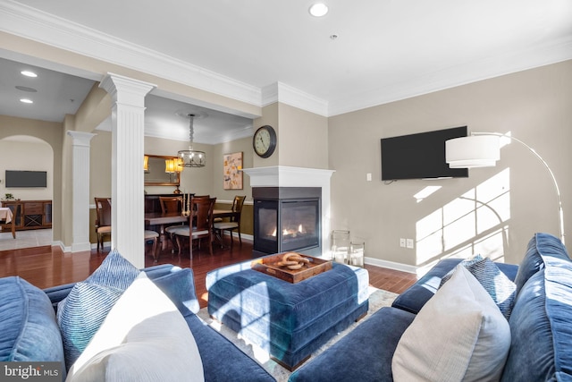 living room with dark hardwood / wood-style flooring, crown molding, and decorative columns