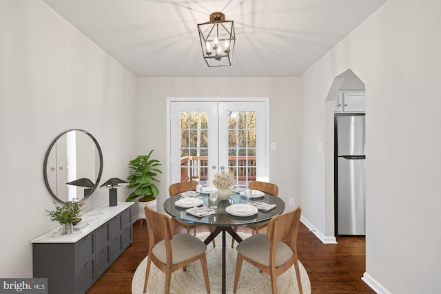 dining space featuring a notable chandelier, dark wood-type flooring, and french doors