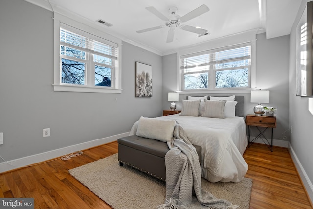 bedroom with wood-type flooring, multiple windows, ceiling fan, and crown molding