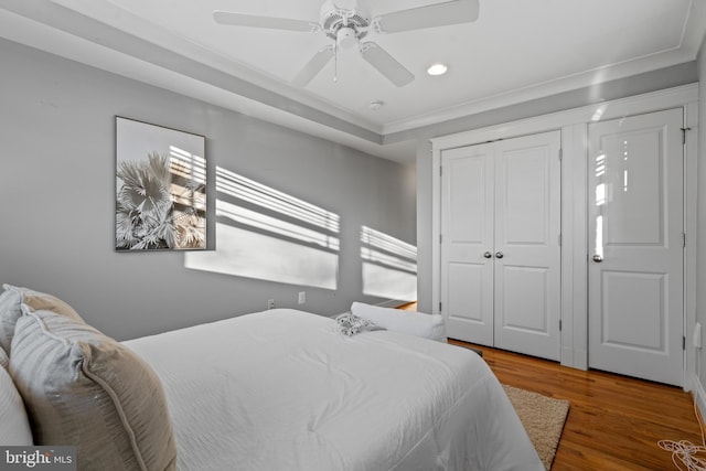 bedroom featuring ceiling fan, a closet, crown molding, and wood-type flooring