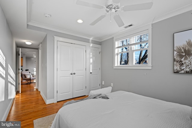 bedroom with a closet, ceiling fan, hardwood / wood-style flooring, and ornamental molding