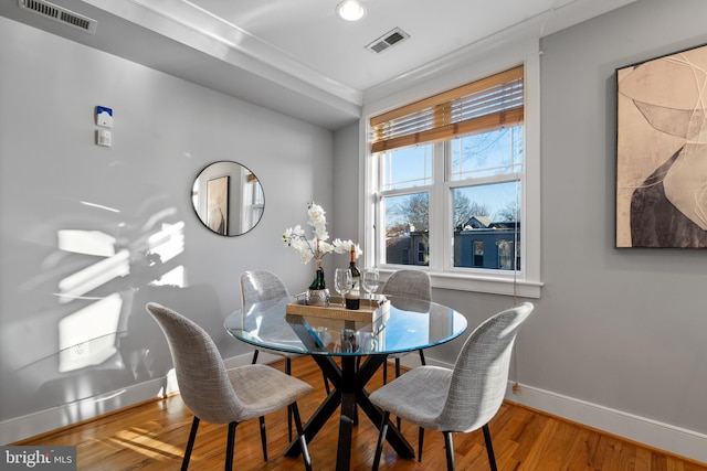 dining space with ornamental molding and wood-type flooring