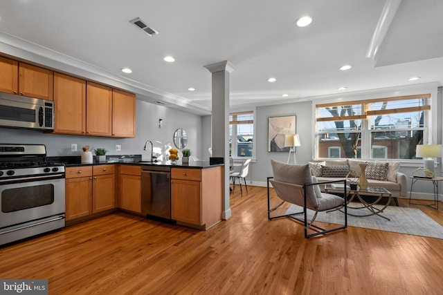 kitchen with stainless steel appliances, sink, kitchen peninsula, light hardwood / wood-style flooring, and crown molding