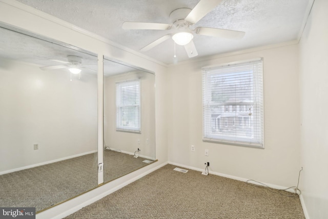 empty room with carpet, a healthy amount of sunlight, crown molding, and a textured ceiling