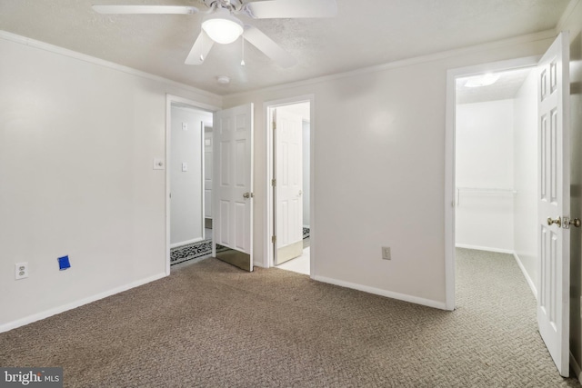 unfurnished bedroom featuring carpet flooring, a closet, ceiling fan, and crown molding