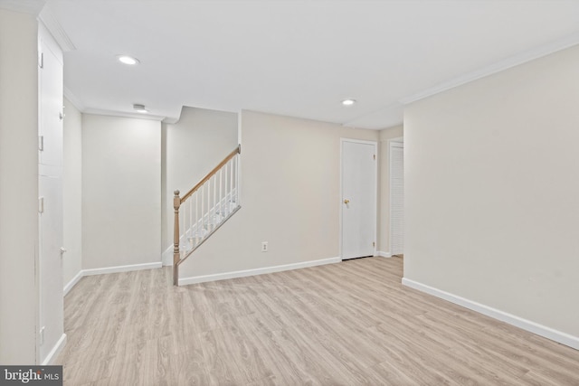 basement with ornamental molding and light hardwood / wood-style floors