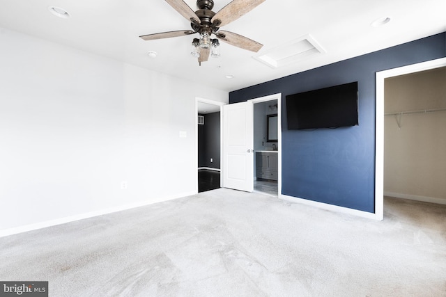 unfurnished bedroom featuring ensuite bathroom, a spacious closet, light colored carpet, ceiling fan, and a closet