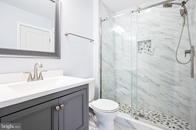 bathroom featuring vanity, a shower with door, and toilet