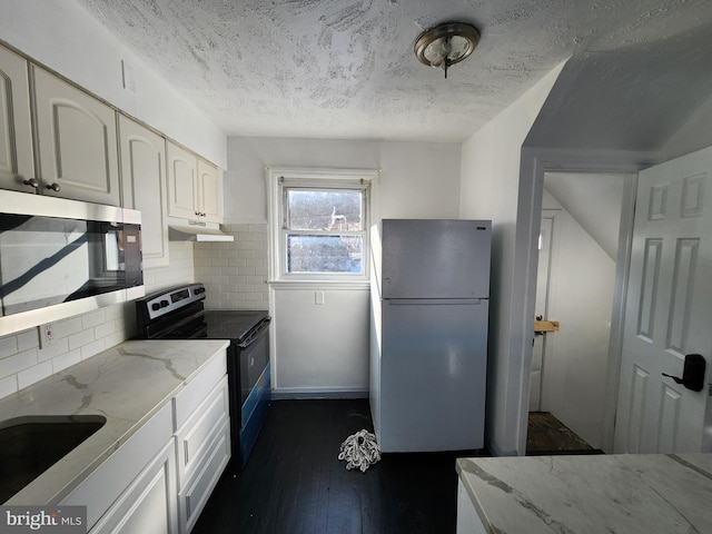 kitchen with tasteful backsplash, light stone counters, white fridge, white cabinetry, and black / electric stove