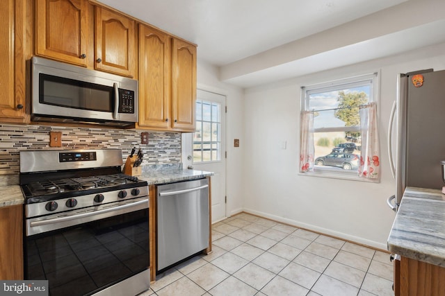 kitchen with light stone counters, light tile patterned floors, tasteful backsplash, a healthy amount of sunlight, and appliances with stainless steel finishes