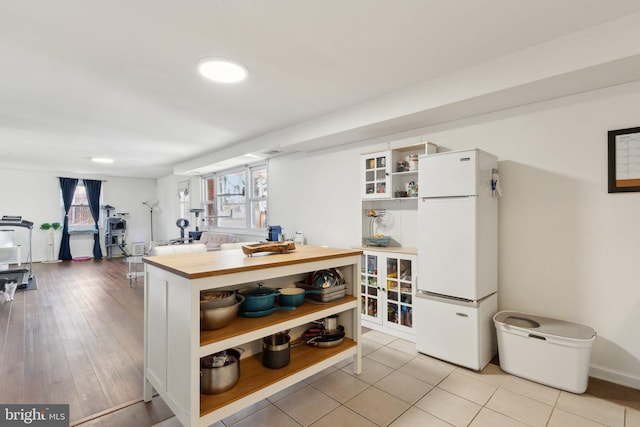 kitchen featuring white refrigerator, white cabinetry, wood counters, and light tile patterned flooring