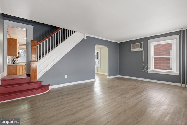 unfurnished living room with a wall mounted AC, crown molding, and wood-type flooring