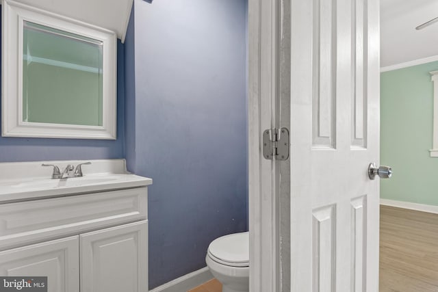 bathroom featuring wood-type flooring, vanity, toilet, and crown molding