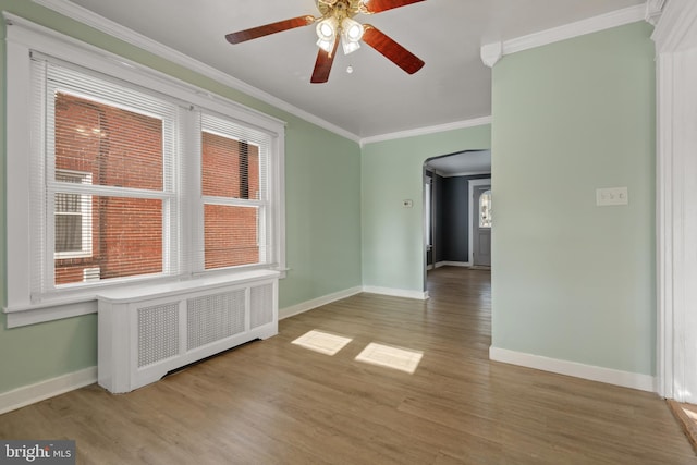 empty room with light wood-type flooring, radiator, ornamental molding, and ceiling fan