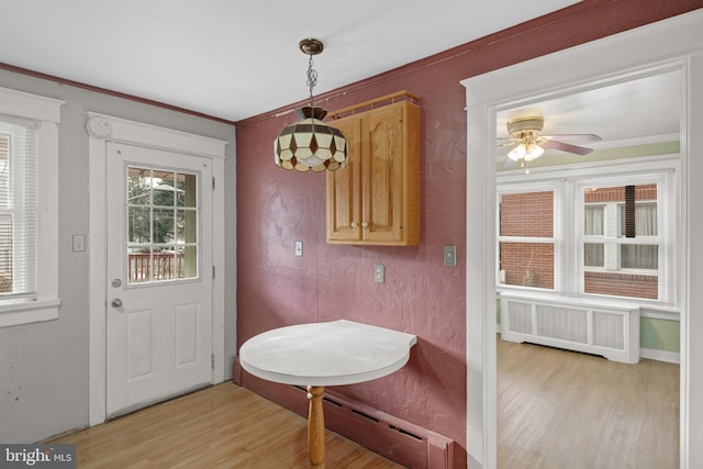 doorway to outside with ceiling fan, radiator heating unit, crown molding, and light hardwood / wood-style flooring