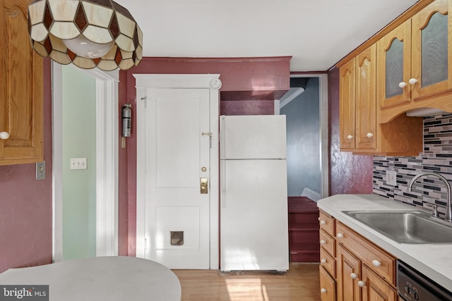 kitchen with light wood-type flooring, backsplash, dishwashing machine, sink, and white fridge