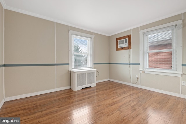 empty room featuring a wall mounted air conditioner, radiator heating unit, hardwood / wood-style flooring, and ornamental molding