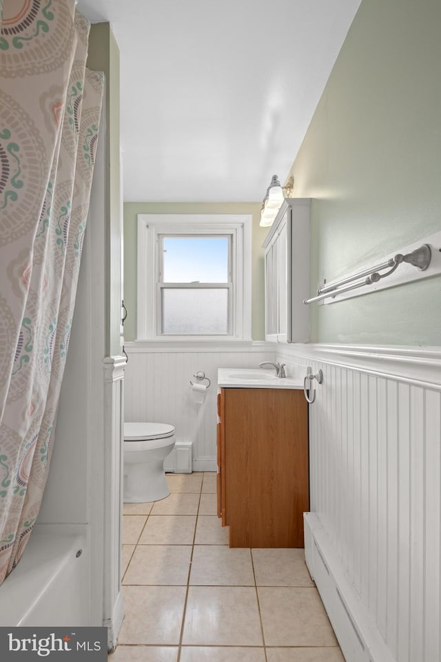 full bathroom with shower / bathtub combination with curtain, tile patterned flooring, a baseboard heating unit, toilet, and vanity