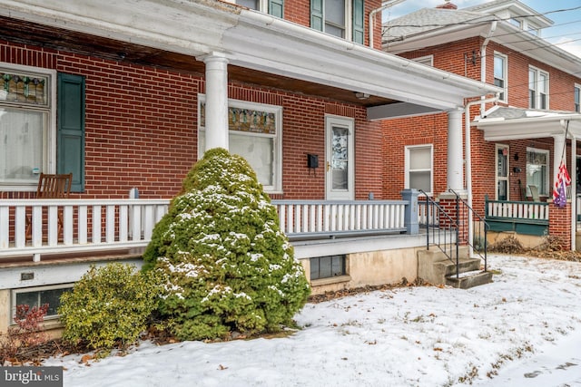 snow covered property entrance with a porch