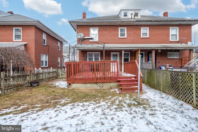 snow covered back of property with a wooden deck