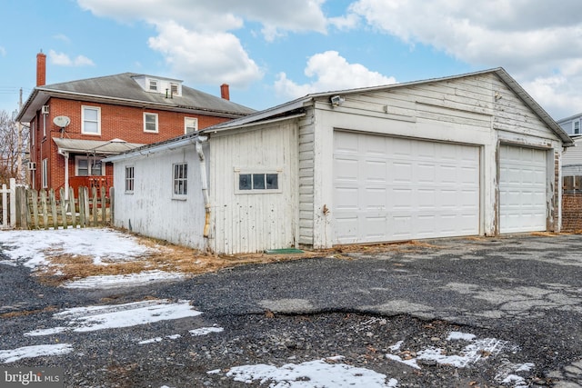 snow covered property featuring an outbuilding and a garage