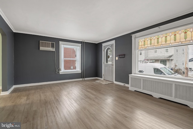 foyer entrance with hardwood / wood-style flooring, an AC wall unit, ornamental molding, and radiator