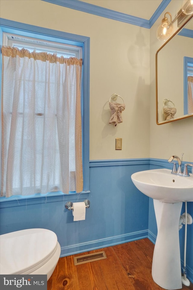 bathroom featuring toilet, hardwood / wood-style flooring, ornamental molding, and sink