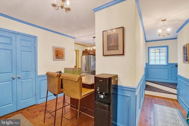 dining area with wood-type flooring, crown molding, and a notable chandelier