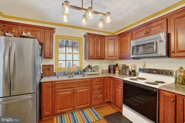 kitchen with sink, ornamental molding, light stone countertops, pendant lighting, and appliances with stainless steel finishes